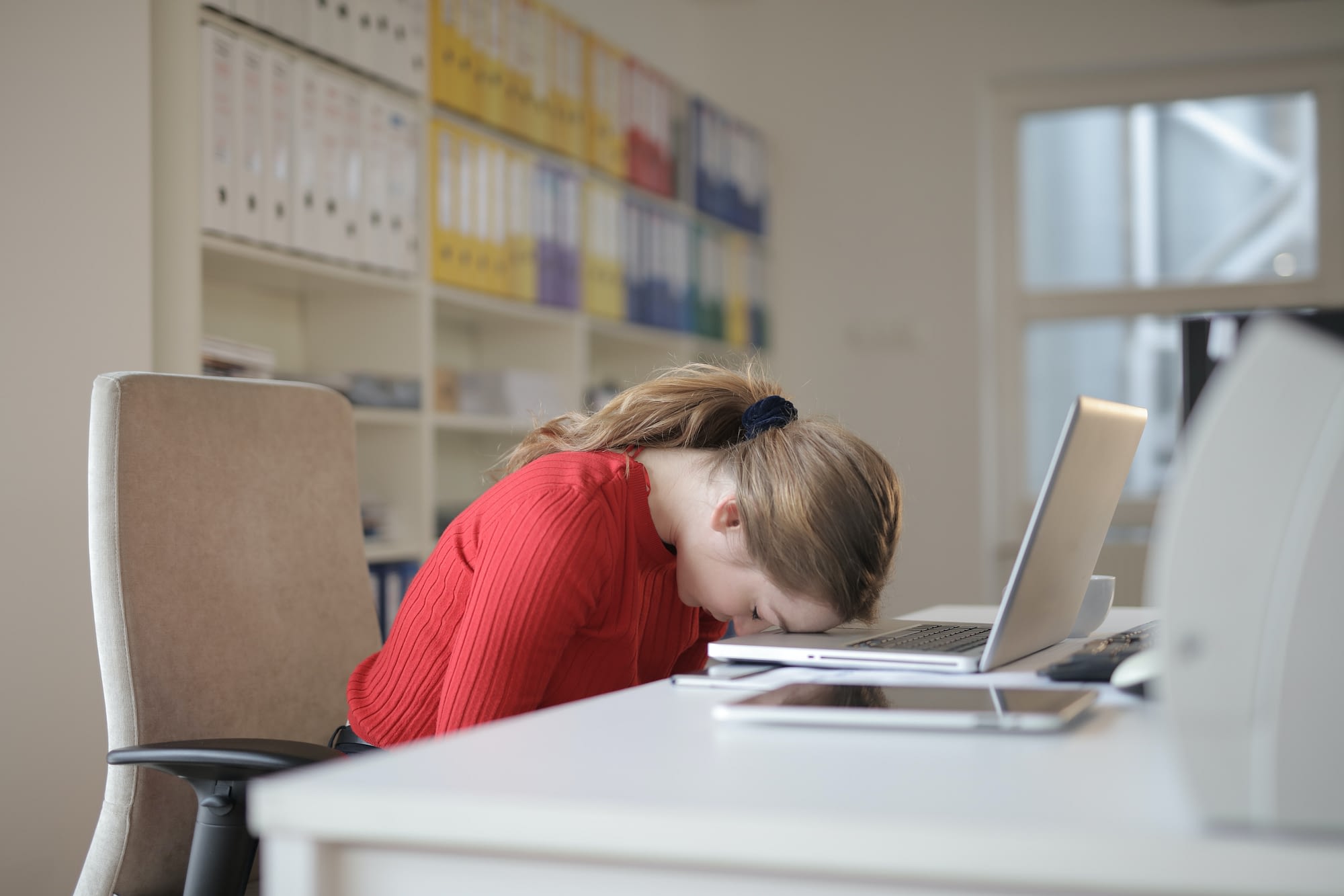 woman in office with head down on computer looking defeated