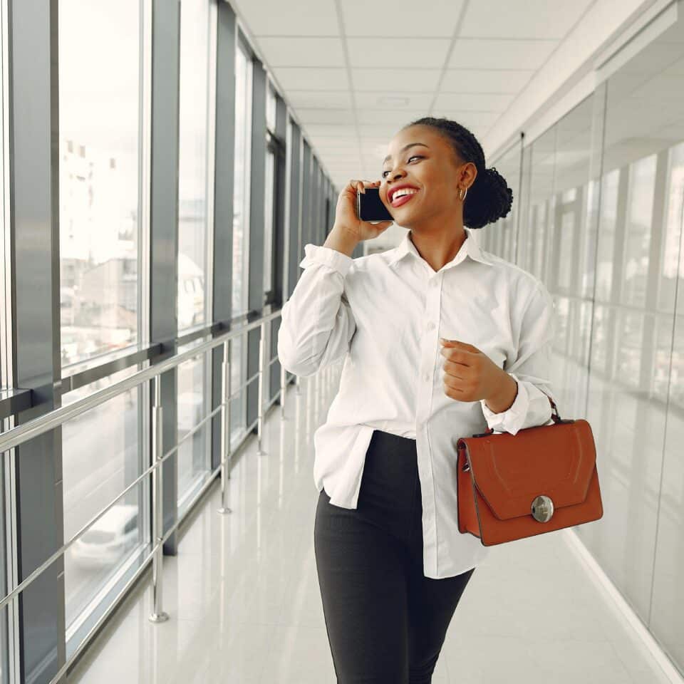 Black woman walking in hallway talking on cellphone